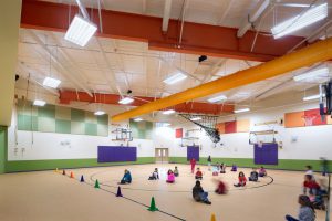 Adaptive reuse elementary school with colorful gym. The space used to be an industrial warehouse in Austin.