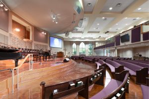 Worship space with curved wood pews blends traditional elements in contemporary church design for Woodlawn Baptist.
