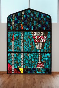 Mid-Century faceted glass window repurposed for bimah after arson attack damages sanctuary.