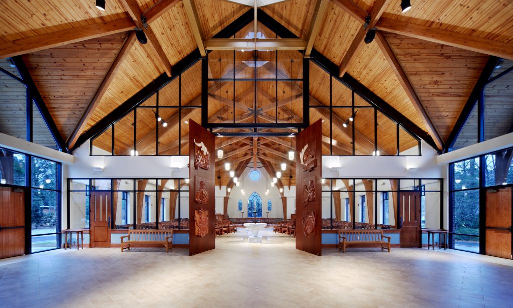 Contemporary church nave with liturgical art doors, view from narthex. Holy Trinity Episcopal by Heimsath Architects.