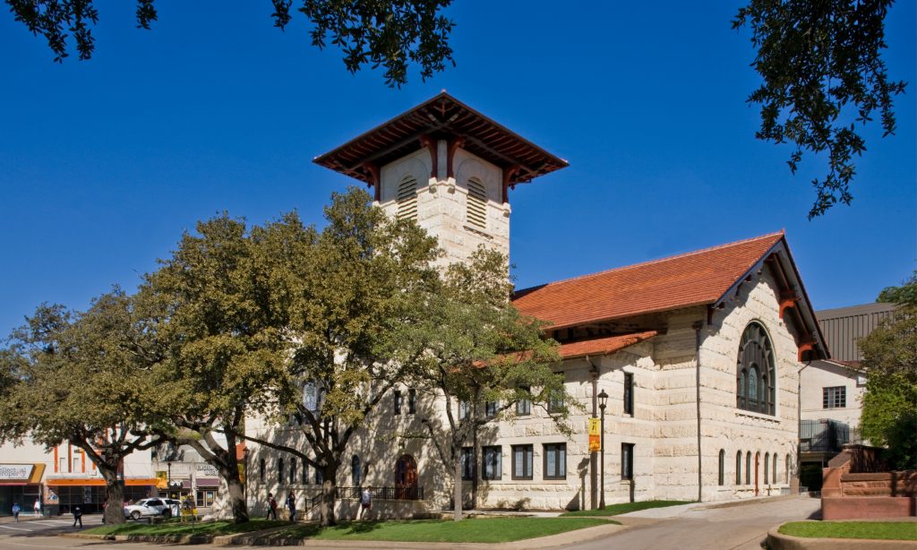 Historic Richardsonian stone church with tower and red tile roof. Preservation project by Heimsath Architects.