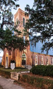 Restored historic brick church with oak trees in downtown Tallahassee. St. John’s Episcopal by Heimsath Architects.