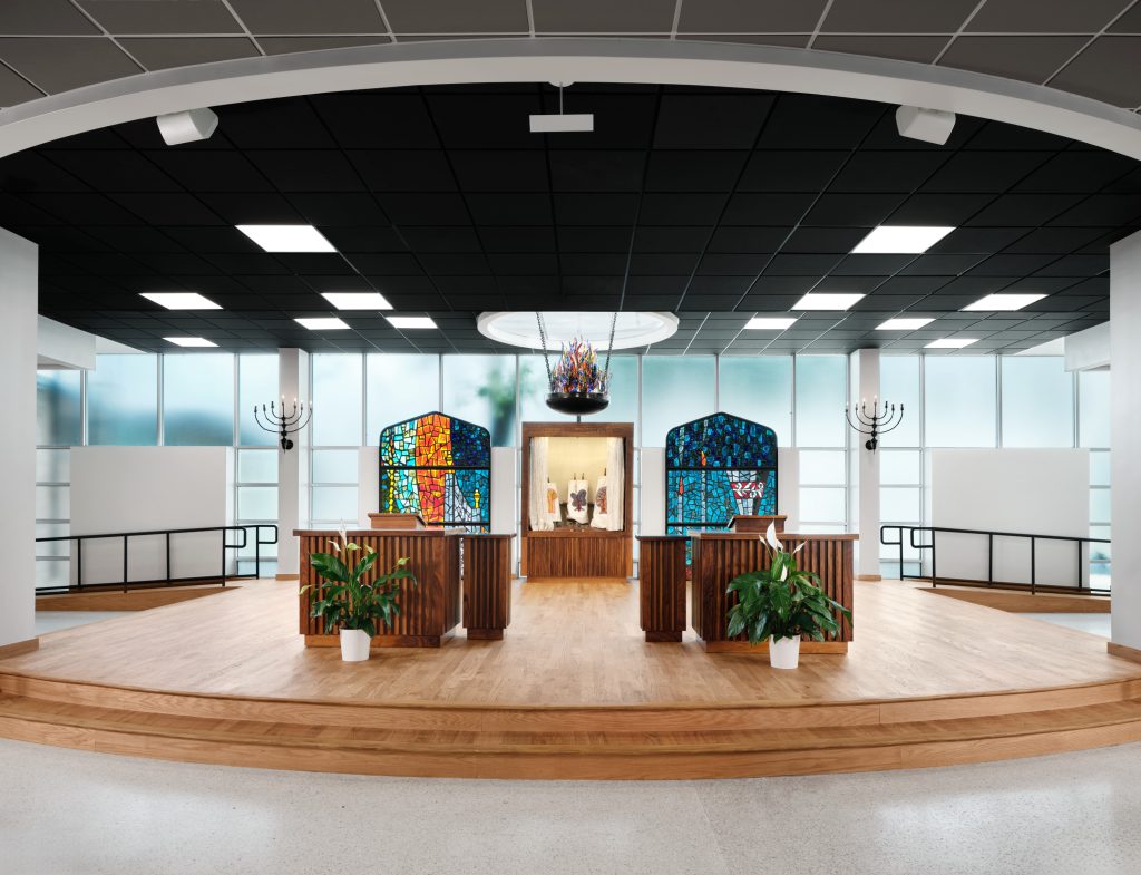 Bimah with arc, ner tamid, and recovered stained glass for transitional worship by Heimsath Architects.